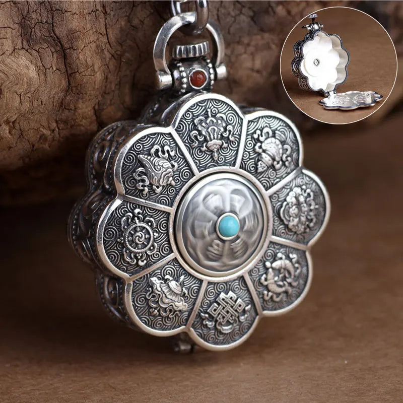 Decorative silver pendant with intricate designs and a turquoise stone on a brown background.