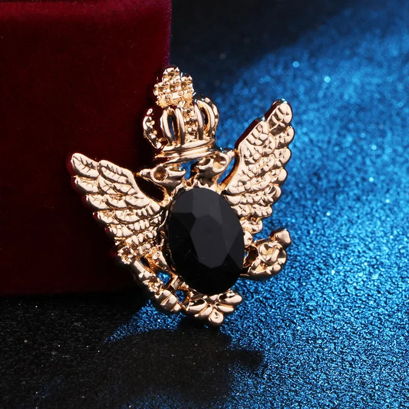 Gold angel brooch with black gemstone luxury fashion jewelry on blue and red fabric background