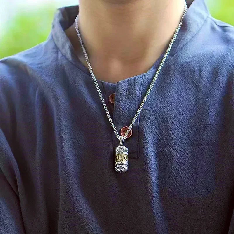 Person wearing a necklace with a pendant on a blurred green background