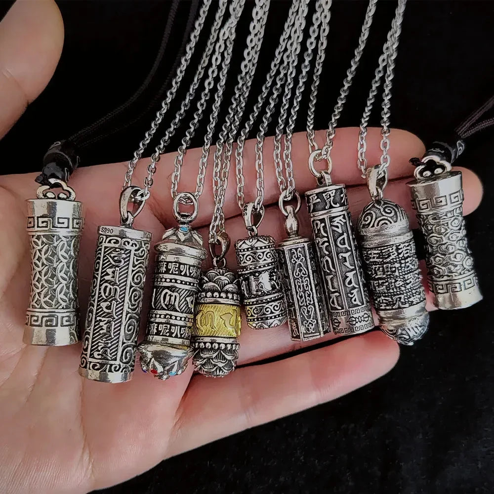 Collection of silver necklaces with various pendants held in a hand against a black background.