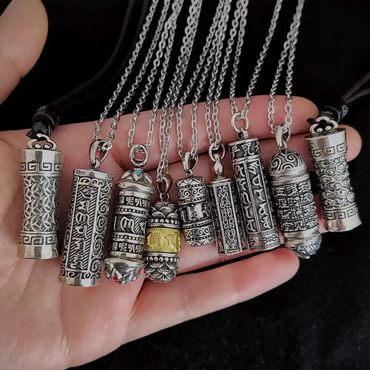 Collection of silver necklaces with various pendants held in a hand against a black background.