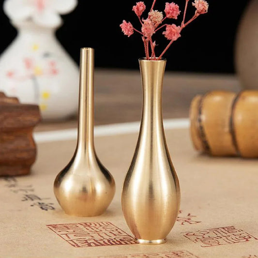 Two gold vases on a textured surface with a blurred background