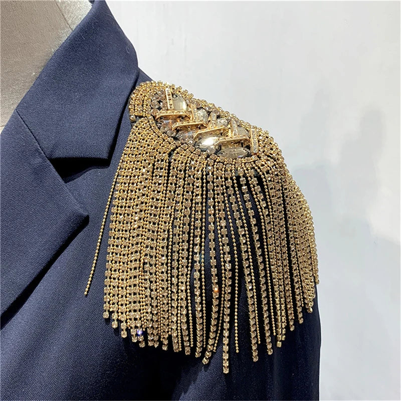 Gold tassel shoulder jewelry accessory on dark fabric background