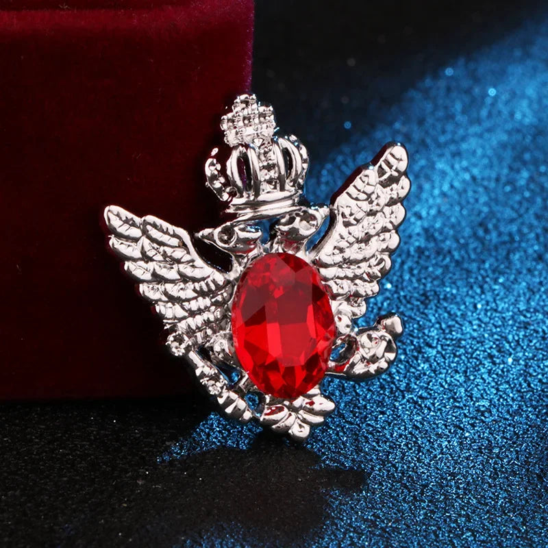 silver angel brooch with red gemstone luxury fashion jewelry on blue and red fabric background