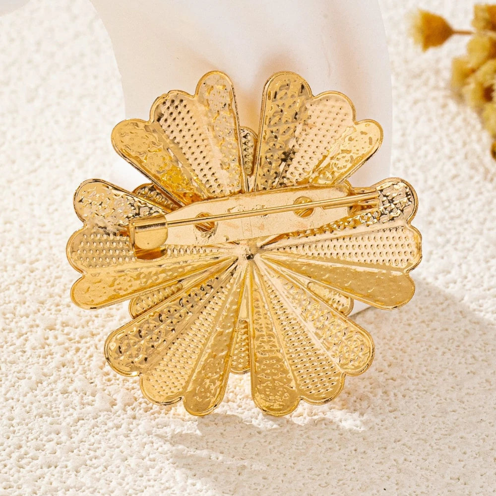Gold flower brooch pin back side view on beige fabric background